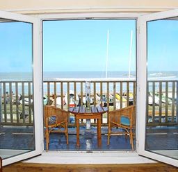 A balcony with two chairs and a table overlooking the sea at Trysor Y Mor in Borth