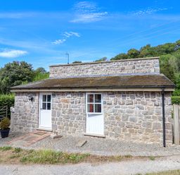 A stone building with double doors and a gravel path at The Lambing Shed in Dyserth near Prestatyn