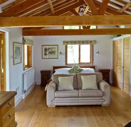 A bedroom with wooden beams a sofa bed a wooden floor and a wardrobe at The Springs in Ashey near Brading and Ryde