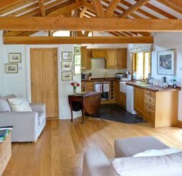 A living room and kitchen area with wooden beams and furniture at The Springs in Ashey near Brading and Ryde