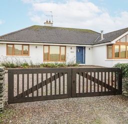 A house with a wooden gate and gravel driveway at Lough Cluhir Cottage Union Hall, County Cork