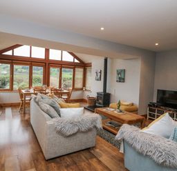 A living room with a dining area and large windows at Lough Cluhir Cottage in Union Hall, County Cork