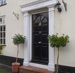 A black front door with the number 25 and two potted small trees on either side at Teds Place in Aylsham