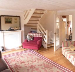 A living room with armchairs a sofa a patterned rug and a staircase at Teds Place in Aylsham