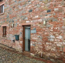 A stone exterior wall of a building with windows a glass door and a mailbox at Blencathra Barn in Penrith