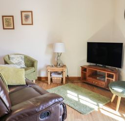 A living room with a tv and sofa at Lily Cottage in Caeathro near Caernarfon