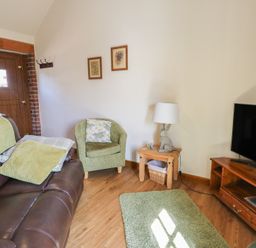 A living room with a sofa and television at Lily Cottage in Caeathro near Caernarfon