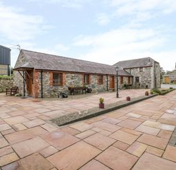 A stone courtyard with benches lamp posts and potted plants at Lavender Cottage in Caeathro near Caernarfon