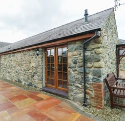 An exterior view of a stone building with double doors at Lavender Cottage Caeathro near Caernarfon