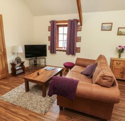 A living room with a sofa and television at Lavender Cottage Caeathro near Caernarfon