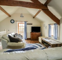 A living room with a sofa and television at Bluebell Cottage in Caeathro near Caernarfon