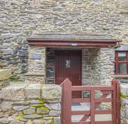 Entrance to a stone barn with a wooden door and gate at Hill Side Barn in Pennington near Ulverston