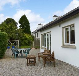 An outdoor patio area with wooden chairs and table and plastic chairs around a round table at The Range in Enniscorthy County Wexford