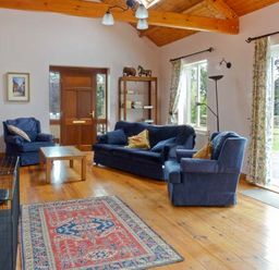 A living room with blue sofas a wooden coffee table a patterned rug and wooden ceiling beams at The Range in Enniscorthy County Wexford