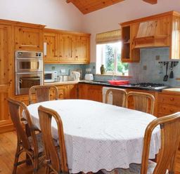 A kitchen with wooden cabinets dining table with white tablecloth and wooden chairs at The Range in Enniscorthy County Wexford