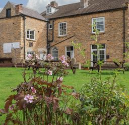 A garden with flowers and a building in the background at The Lodge in Snainton near Scarborough