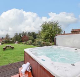A garden with a hot tub and picnic tables at The Lodge in Snainton near Scarborough