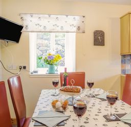 A dining table with wine glasses bottles eggs and cake in a kitchen at Ty Nant in Betws-y-Coed
