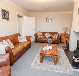 A living room with brown leather sofas a wooden coffee table and a fireplace at Bryn Seion in Y Felinheli