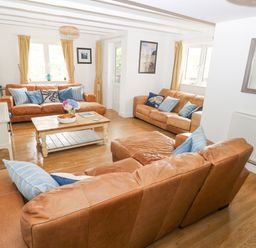 A living room with three brown leather sofas a wooden coffee table and a television at Hillbrook House in Nolton Haven