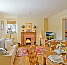 A living room with a fireplace a sofa and a dining table set at The Old Farmhouse in Lowick