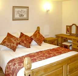 A bedroom with a wooden bed and furniture including a dressing table at Happy Union Stables in Abbeycwmhir near Rhayader