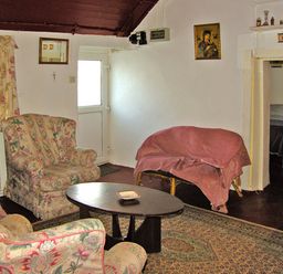 A living room with floral upholstered armchairs a wooden coffee table and a small sofa with a pink cover at Carthys Cottage in Kilbrien near Dungarvan County Waterford