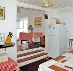 A kitchen with a microwave knife block and fridge with tables covered with checkered and white tablecloths at Carthy's Cottage Kilbrien near Dungarvan County Waterford