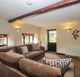 A living room with a sofa and a door at Woodside Barn Pennington near Ulverston