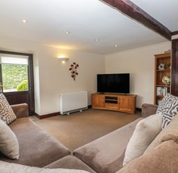 A living room with a sofa and television at Woodside Barn Pennington near Ulverston
