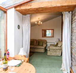 A living room with two beige sofas a wooden dining table and a glass window at The Stable in Milton near Brampton
