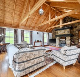 A living room with sofas, a coffee table, and a fireplace at Chapel Green in Polgooth