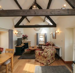 A living room with wooden beams a dining table armchairs and a fireplace at Barn Cottage High Normanby near Robin Hoods Bay