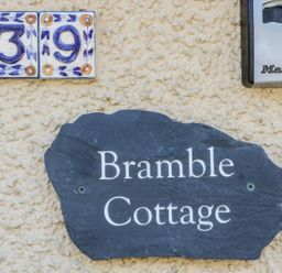 House number 39 in decorative tiles a black slate sign with Bramble Cottage and a silver Master Lock key safe on a textured wall at Bramble Cottage in Sedbergh