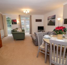 A living room with sofas dining table and chairs near stairs at No 1 Railway Cottages in Betws-y-Coed