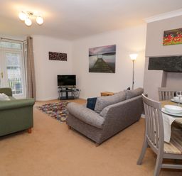 A living room with sofas and a television near a dining table at No 1 Railway Cottages in Betws-y-Coed