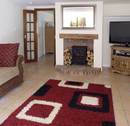 A living room with a sofa cushions fireplace and television on a wooden stand at Rosewaters Cottage Astley Burf near Stourport-on-Severn