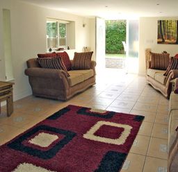 A living room with two brown sofas and a patterned rug at Rosewaters Cottage in Astley Burf near Stourport-on-Severn