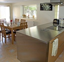 A kitchen with a stainless steel countertop and a wooden dining table with chairs at Rosewaters Cottage in Astley Burf near Stourport-on-Severn