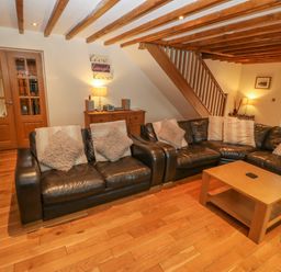 A living room with brown leather sofas cushions wooden coffee table wooden beams on ceiling at Cefn-Yr-Efail in Golan near Porthmadog
