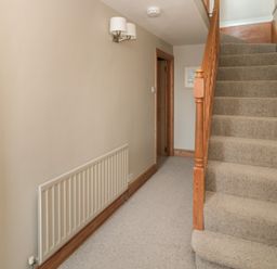 A hallway with carpeted stairs and a radiator at Jackson Cottage in Alnmouth