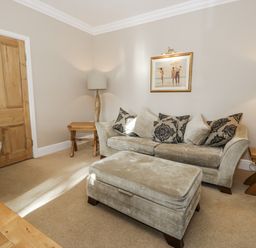 A living room with a sofa and ottoman at Tyddyn Goronwy in Talybont
