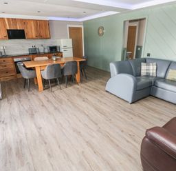 A living room with a kitchen area and dining table at Meadow View in Laugharne
