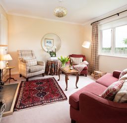 A living room with red couches a plaid armchair a wooden coffee table and a fireplace at Barmoor Ridge in Lowick near Holy Island
