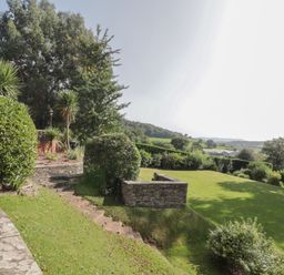 A garden with stone steps bushes and trees overlooking fields at The Croft in Vowchurch near Peterchurch