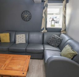 A living room with a grey sofa and wooden coffee table at Dylan's Court in Laugharne