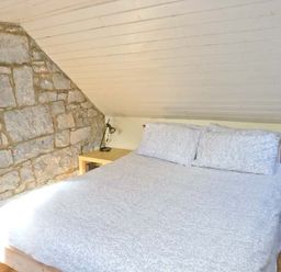 A bedroom with a double bed and stone wall at Clooncorraun Cottage in Ballinrobe County Mayo