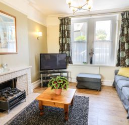 A living room with a fireplace television sofa coffee table and window at Riverside View in Cark in Cartmel