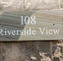 A stone sign with the number 108 and Riverside View on a stone wall at Riverside View in Cark in Cartmel