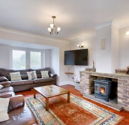 A living room with two brown leather sofas a wooden coffee table a rug fireplace with a wood stove and a wall mounted TV at Ingleside in Adsett Royal Forest of Dean